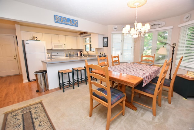 dining room with light colored carpet and a chandelier