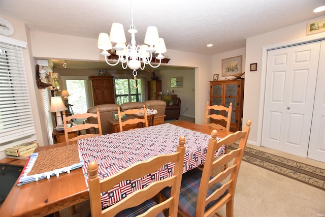 carpeted dining area featuring a textured ceiling and a chandelier