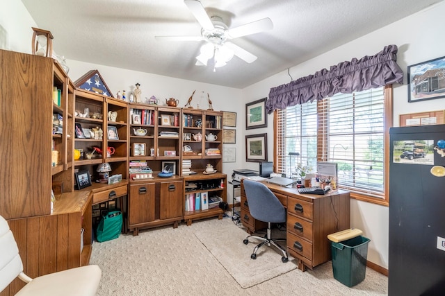 carpeted home office with a textured ceiling and ceiling fan