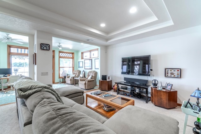 carpeted living room featuring a raised ceiling and ceiling fan