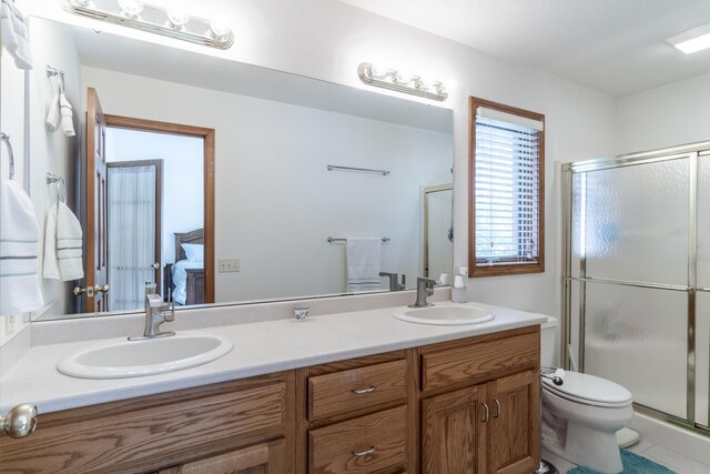 ensuite bathroom with double vanity, a stall shower, connected bathroom, and a sink