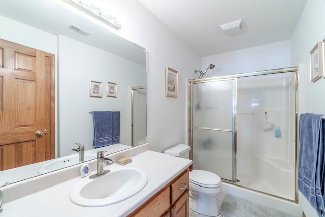 bathroom with tile patterned floors, a shower with shower door, toilet, and vanity