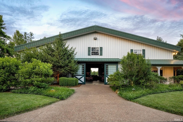 view of front of property featuring concrete driveway, a standing seam roof, metal roof, a carport, and a front lawn