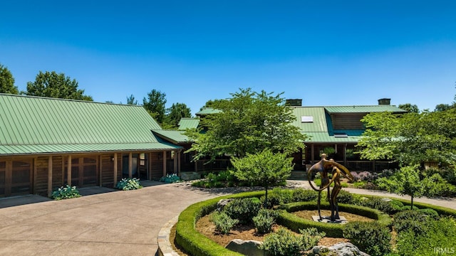 view of front facade with metal roof, driveway, and a standing seam roof