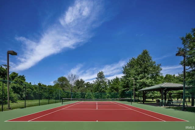 view of tennis court featuring community basketball court, a gazebo, and fence