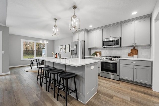 kitchen featuring a sink, appliances with stainless steel finishes, gray cabinets, and light countertops