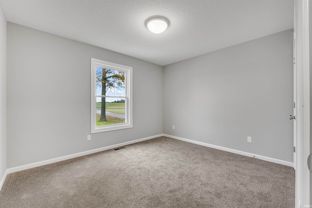 carpeted empty room featuring a textured ceiling