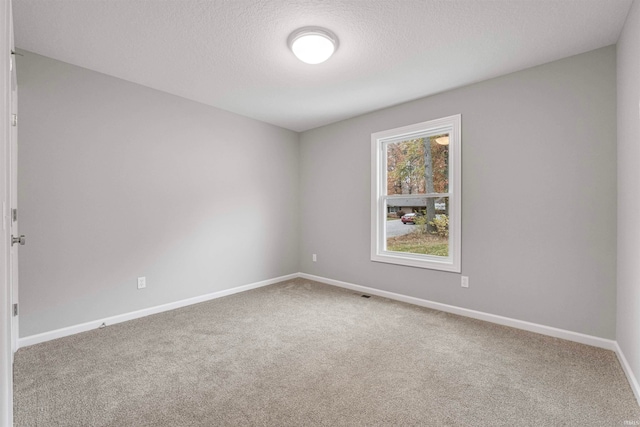 carpeted spare room featuring visible vents, baseboards, and a textured ceiling