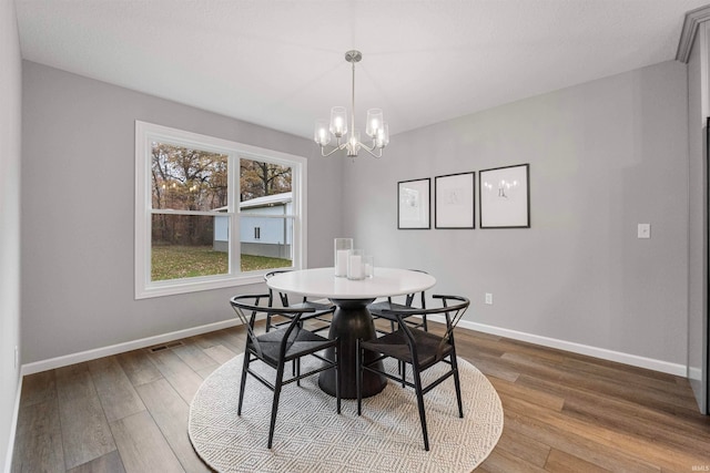 dining area featuring visible vents, baseboards, a chandelier, and wood finished floors