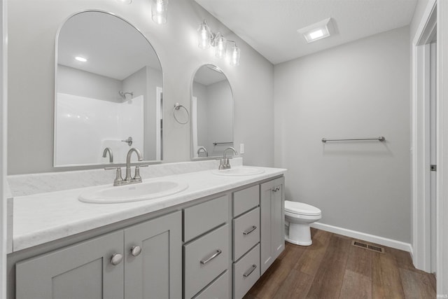 full bath featuring double vanity, visible vents, a sink, and wood finished floors