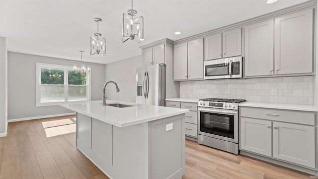 kitchen with light hardwood / wood-style flooring, a kitchen island with sink, stainless steel appliances, and gray cabinetry