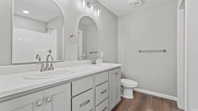 bathroom featuring vanity, toilet, wood-type flooring, and a shower