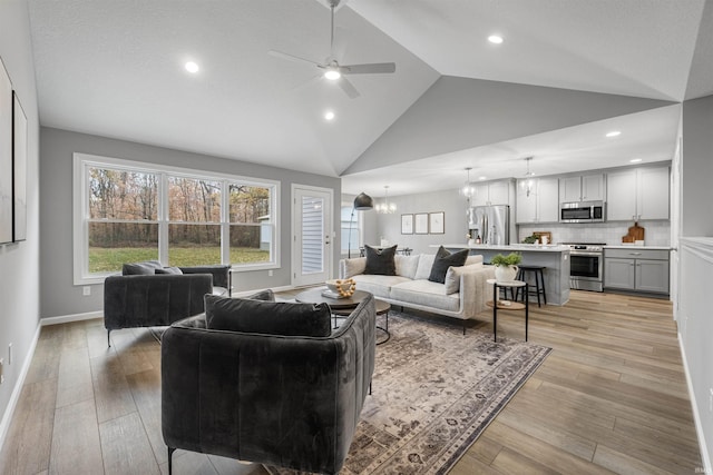 living room with recessed lighting, light wood-style flooring, high vaulted ceiling, baseboards, and ceiling fan with notable chandelier