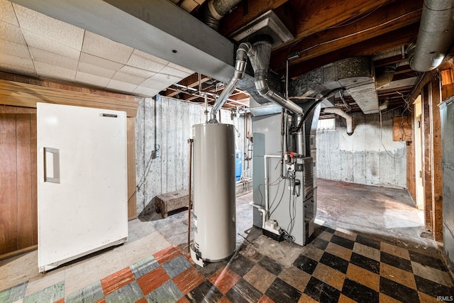 basement featuring tile patterned flooring, gas water heater, heating unit, and wooden walls