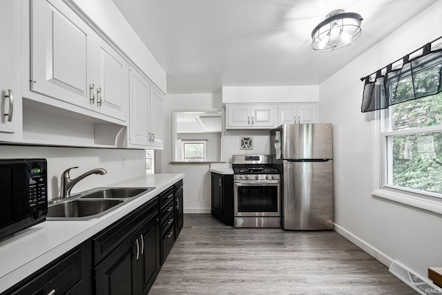 kitchen with sink, light hardwood / wood-style flooring, stainless steel appliances, and white cabinetry