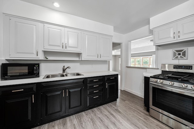 kitchen featuring stainless steel range with gas cooktop, white cabinetry, light wood-type flooring, and sink