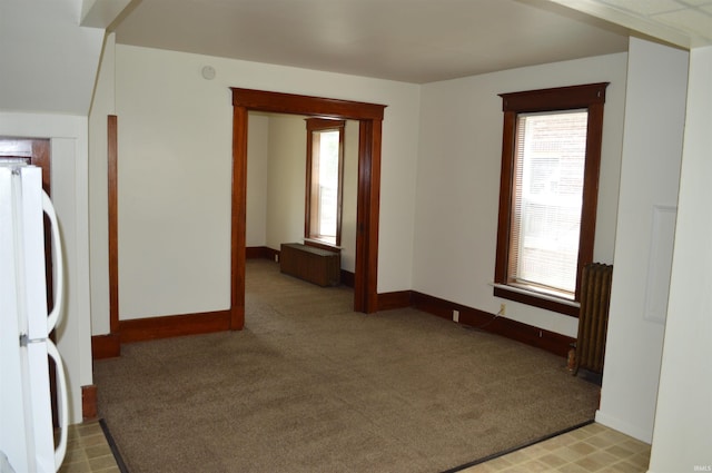 hallway featuring light carpet and radiator heating unit