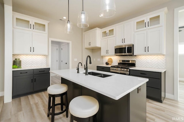 kitchen featuring gray cabinetry, white cabinetry, a kitchen island with sink, and appliances with stainless steel finishes