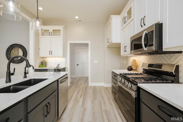 kitchen with white cabinetry, sink, hanging light fixtures, and appliances with stainless steel finishes