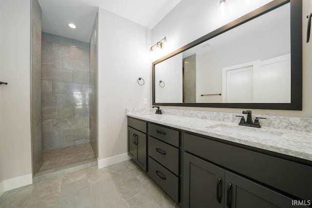 bathroom with a tile shower and vanity