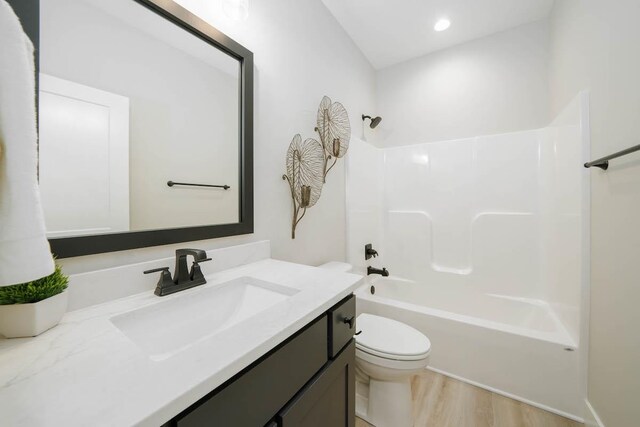 full bathroom with hardwood / wood-style floors, vanity, toilet, and shower / washtub combination