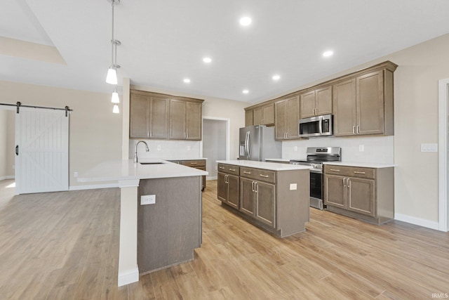 6711 W Division Line Rd, Delphi, IN 46923 - kitchen featuring backsplash, appliances with stainless steel finishes, a barn door, a sink, and a peninsula