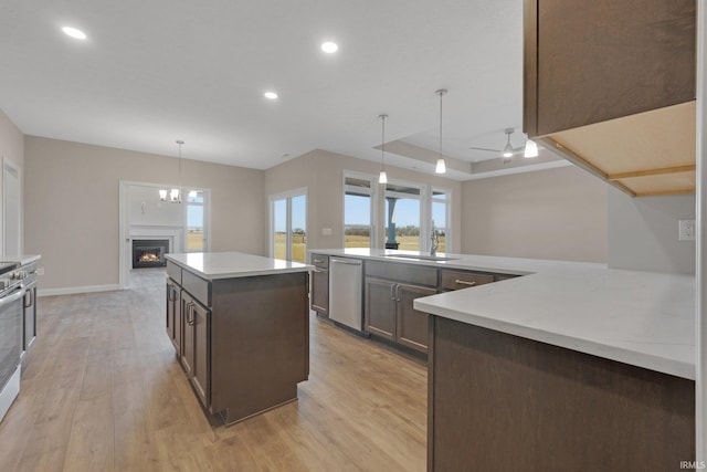 kitchen with appliances with stainless steel finishes, pendant lighting, sink, a center island, and light wood-type flooring