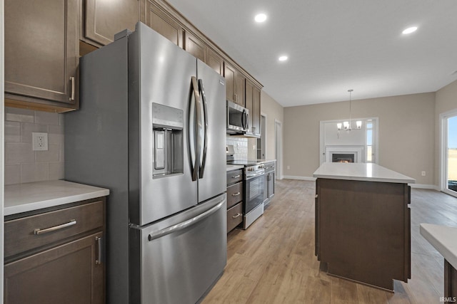 kitchen featuring pendant lighting, decorative backsplash, stainless steel appliances, and a kitchen island