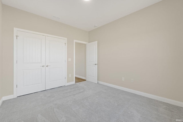 unfurnished bedroom featuring light colored carpet and a closet