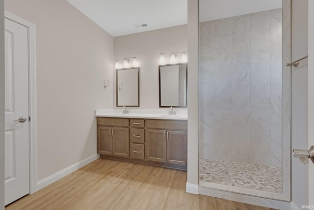 bathroom with tiled shower, vanity, and hardwood / wood-style floors