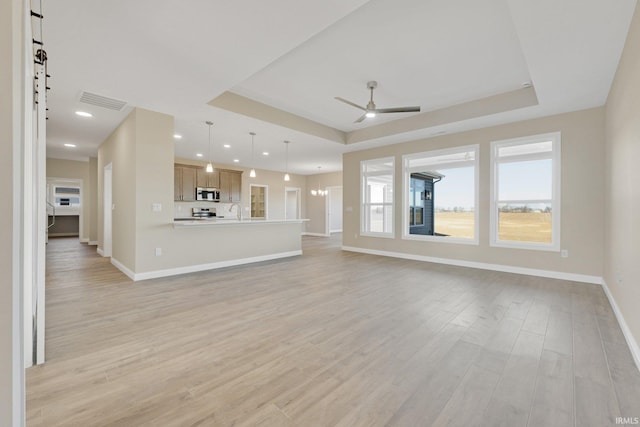 6711 W Division Line Rd, Delphi, IN 46923 - unfurnished living room featuring a ceiling fan, a raised ceiling, baseboards, light wood-style floors, and recessed lighting