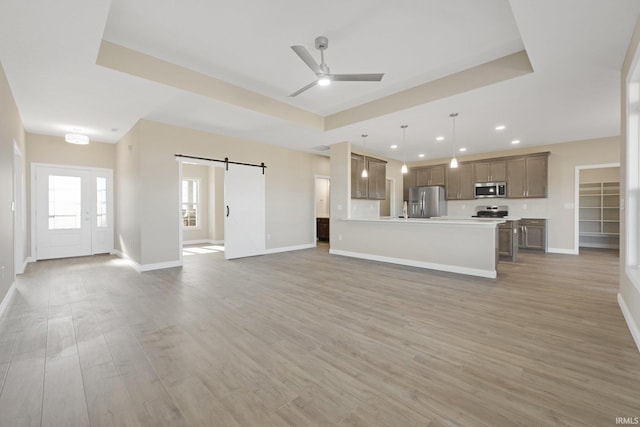 6711 W Division Line Rd, Delphi, IN 46923 - unfurnished living room with baseboards, a barn door, light wood finished floors, and a ceiling fan