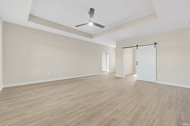 6711 W Division Line Rd, Delphi, IN 46923 - spare room with baseboards, a barn door, a ceiling fan, and a tray ceiling
