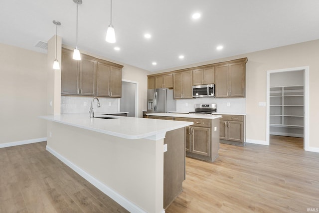 6711 W Division Line Rd, Delphi, IN 46923 - kitchen with a peninsula, baseboards, a sink, light wood-style flooring, and appliances with stainless steel finishes
