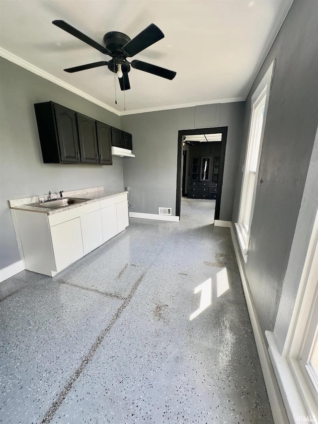 unfurnished living room with ceiling fan, sink, and ornamental molding