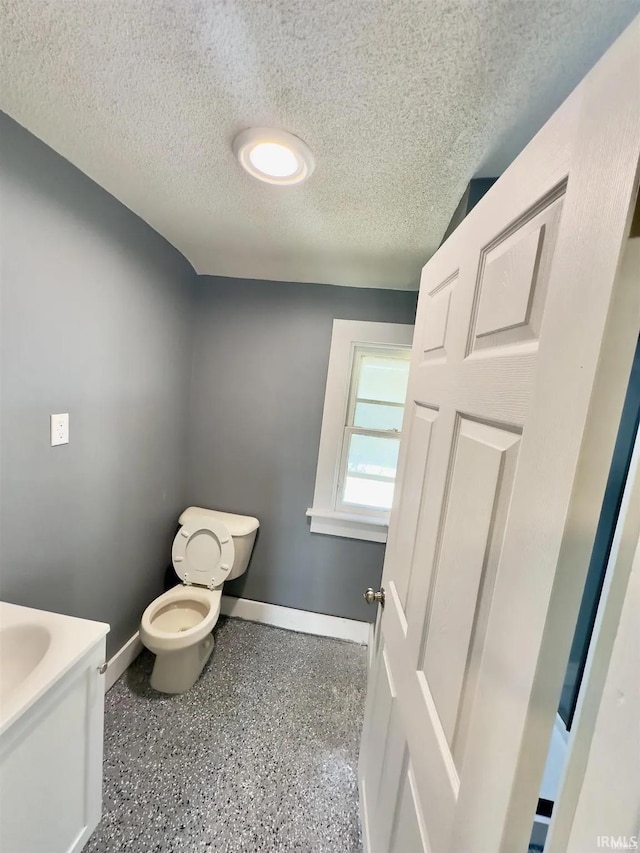 bathroom featuring a textured ceiling, toilet, and vanity