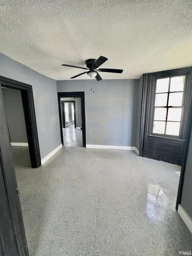 unfurnished room with ceiling fan and a textured ceiling