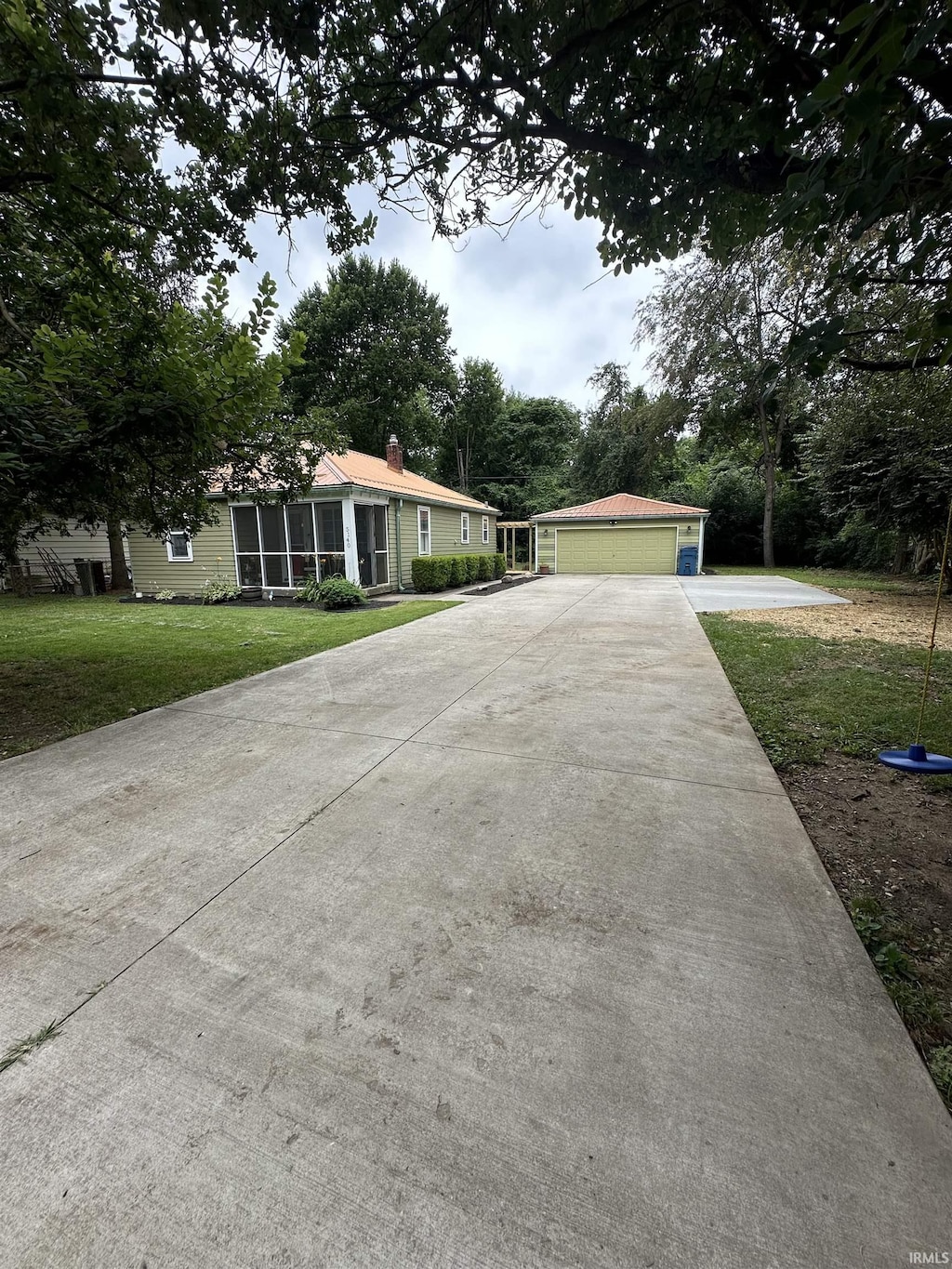 ranch-style house featuring a garage, a front lawn, and a sunroom