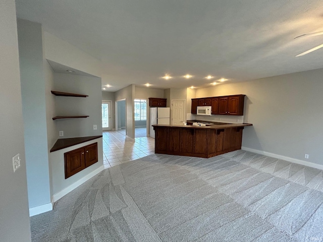 kitchen featuring light carpet, white appliances, and kitchen peninsula