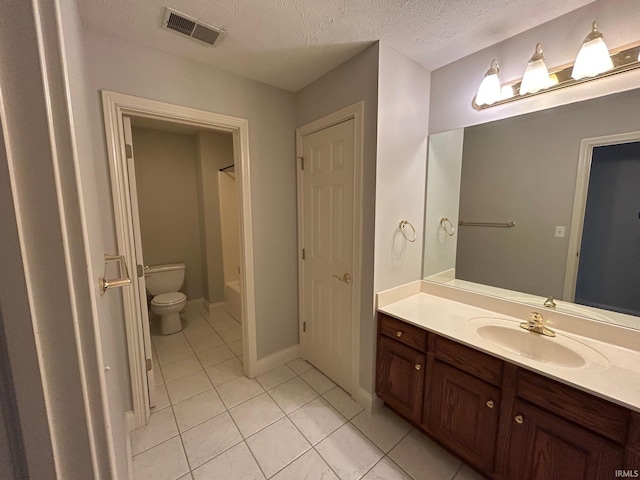 bathroom with tile patterned flooring, vanity, a textured ceiling, and toilet