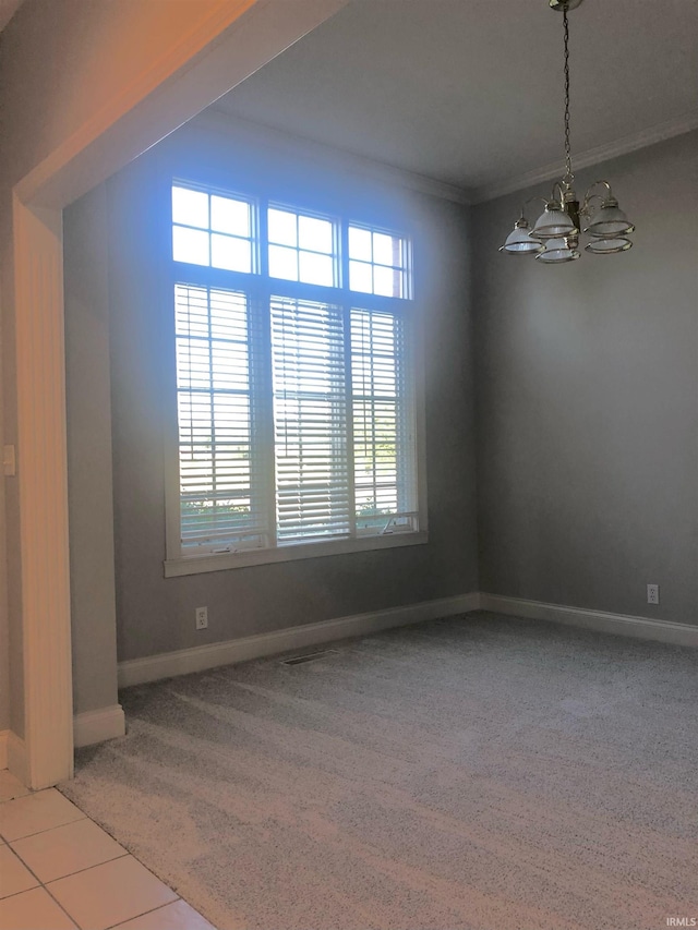 carpeted empty room with a notable chandelier, a wealth of natural light, and ornamental molding