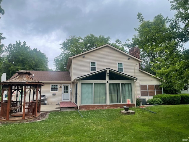 rear view of property featuring a gazebo, a yard, and central AC