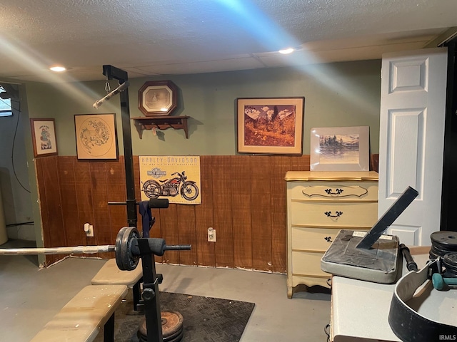 exercise area featuring a textured ceiling and wood walls