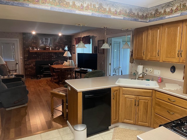 kitchen with sink, a brick fireplace, black dishwasher, decorative light fixtures, and kitchen peninsula