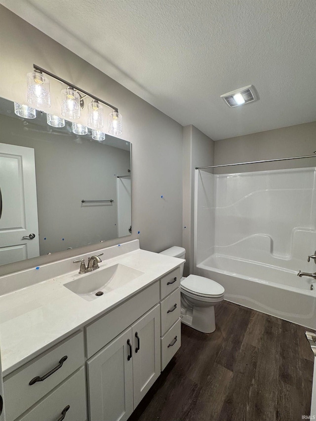 full bathroom with  shower combination, toilet, a textured ceiling, vanity, and hardwood / wood-style flooring