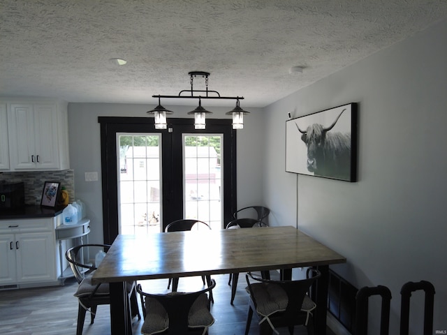 dining area with hardwood / wood-style floors and a textured ceiling