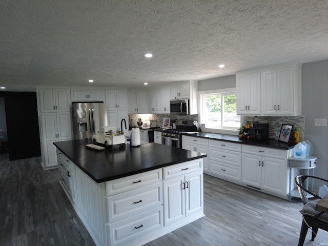 kitchen featuring white cabinetry, stainless steel appliances, dark hardwood / wood-style flooring, and tasteful backsplash