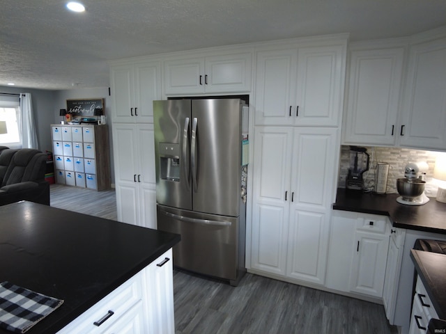 kitchen with dark wood-type flooring, stainless steel fridge, and white cabinets