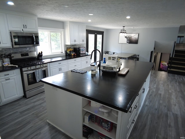 kitchen with stainless steel appliances, dark hardwood / wood-style flooring, a kitchen island with sink, and white cabinets