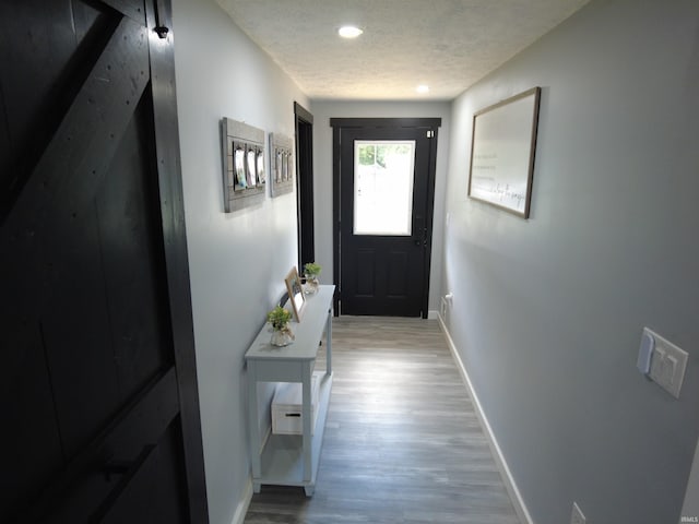 doorway featuring light wood-type flooring and a textured ceiling